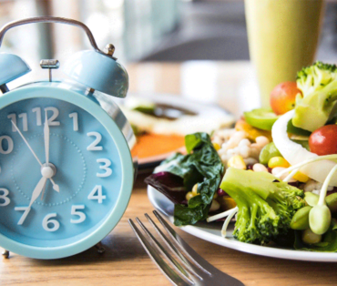 Food on plate with alarm clock next to it