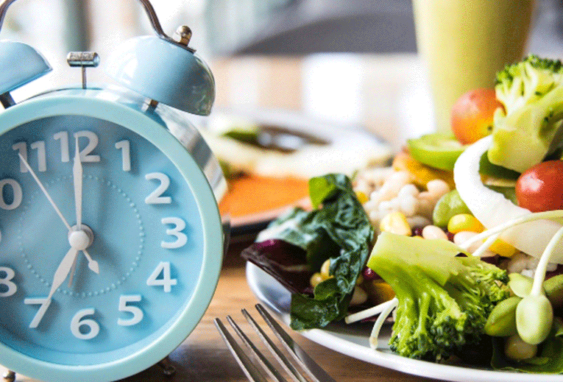Food on plate with alarm clock next to it