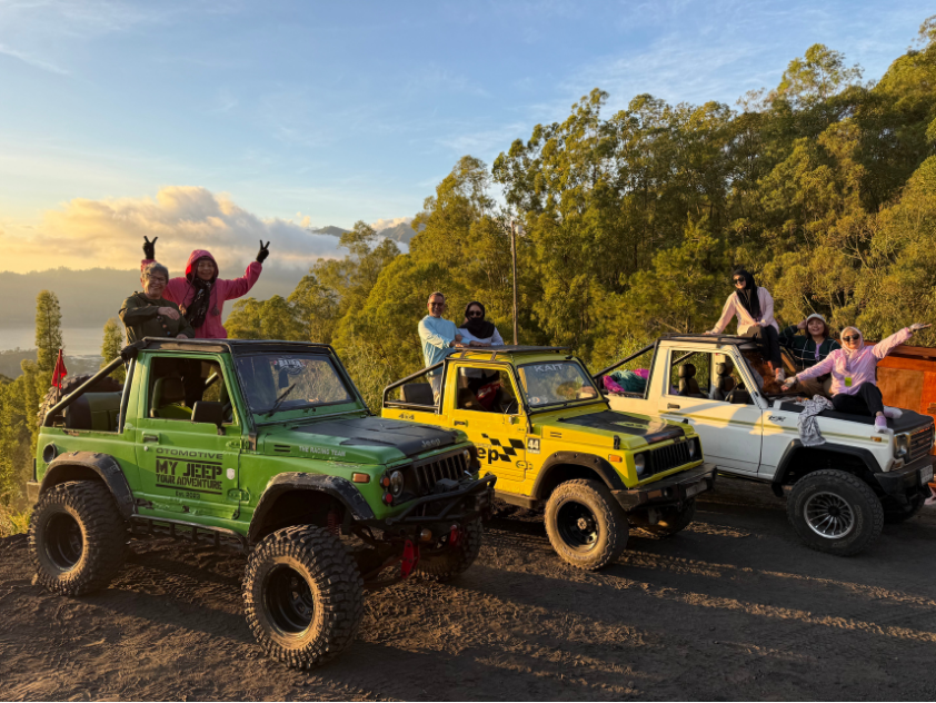Curves Bali Retreat members cheering from green, yellow, and white volcanic tour Jeeps during a Mount Batur sunrise excursion in Bali.
